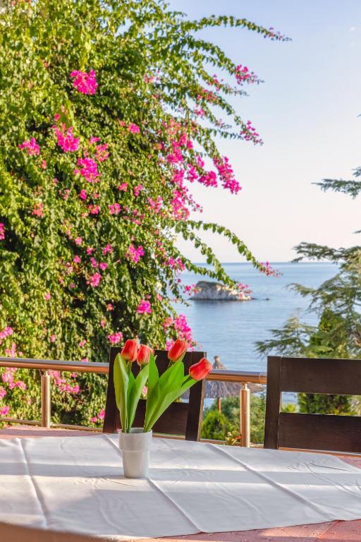 a table with a vase of flowers on a table with roses at Costa Smeralda in Syvota