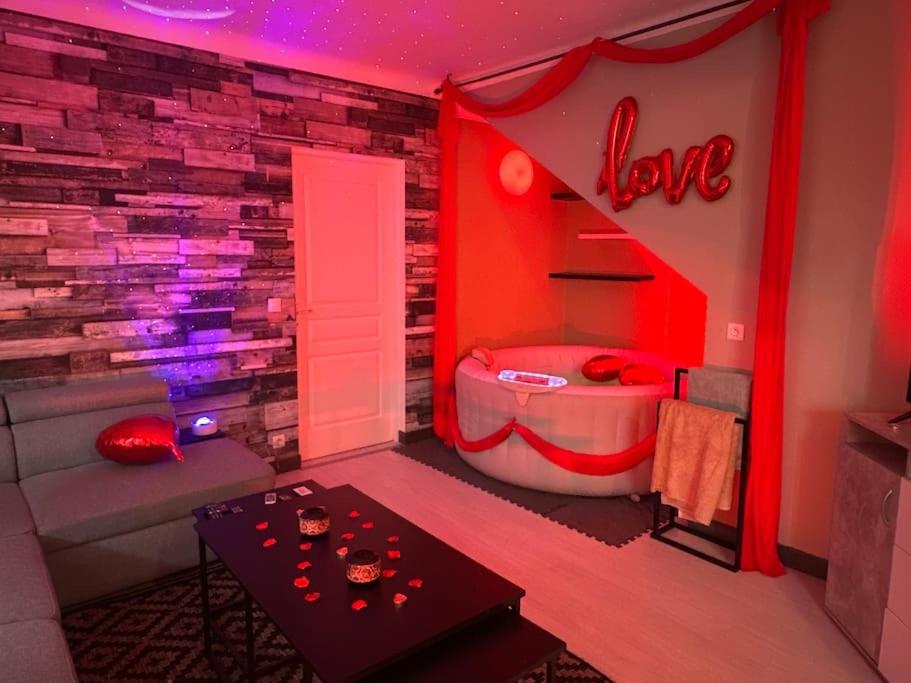 ein rotes Zimmer mit einem Bett und einem Liebesschild in der Unterkunft Love House SPA 3 in Aulnay-sous-Bois