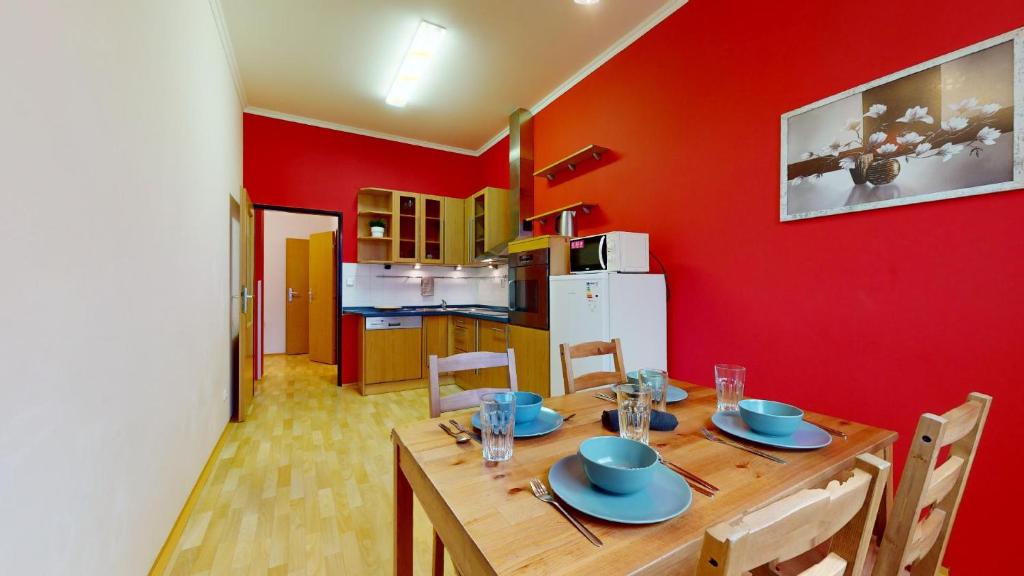 a dining room with a wooden table and a red wall at Apartmán Esser 4 in Milovice