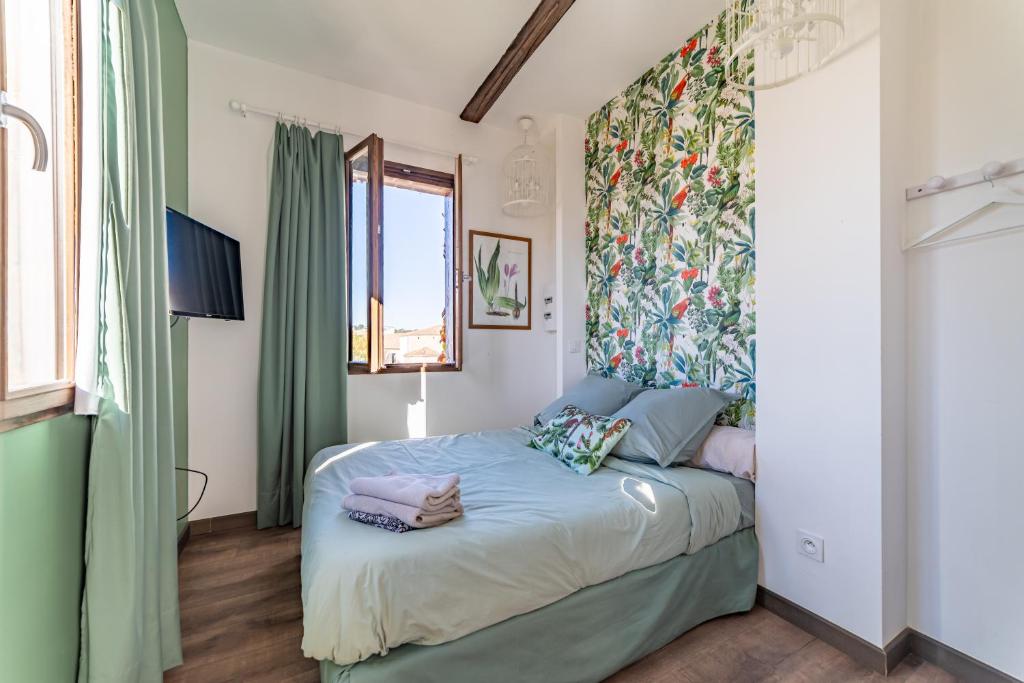 een slaapkamer met een bed met een bloemrijk hoofdeinde bij La Terrasse suspendue des Arènes - Une Nuit à Nîmes in Nîmes