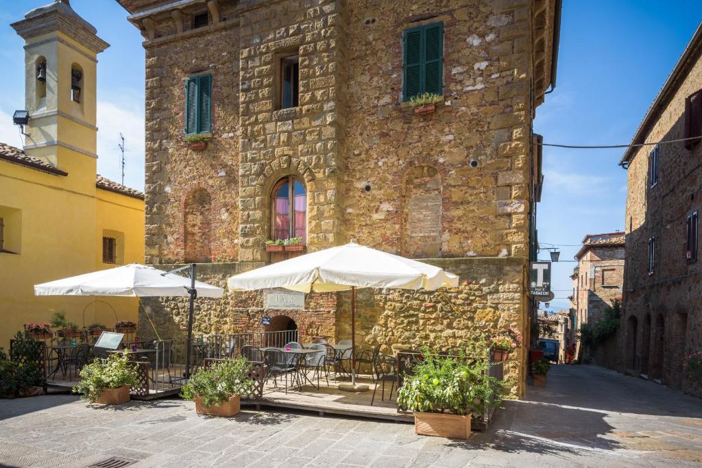 an outdoor patio with tables and umbrellas in front of a building at Locanda di CasalMustia in Castelmuzio