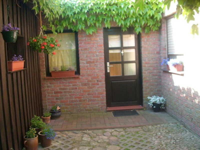 uma casa de tijolos com uma porta preta e vasos de plantas em Ferienwohnung Ziebell em Bollewick