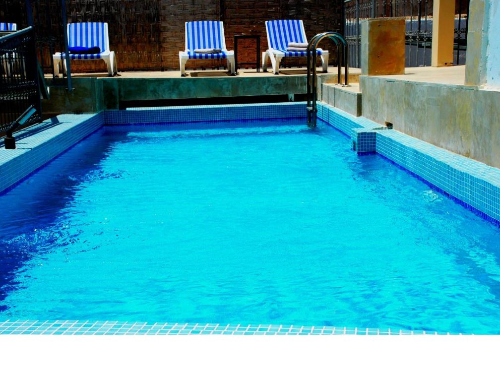 a swimming pool with two blue chairs in it at Riad Marco Andaluz in Sale