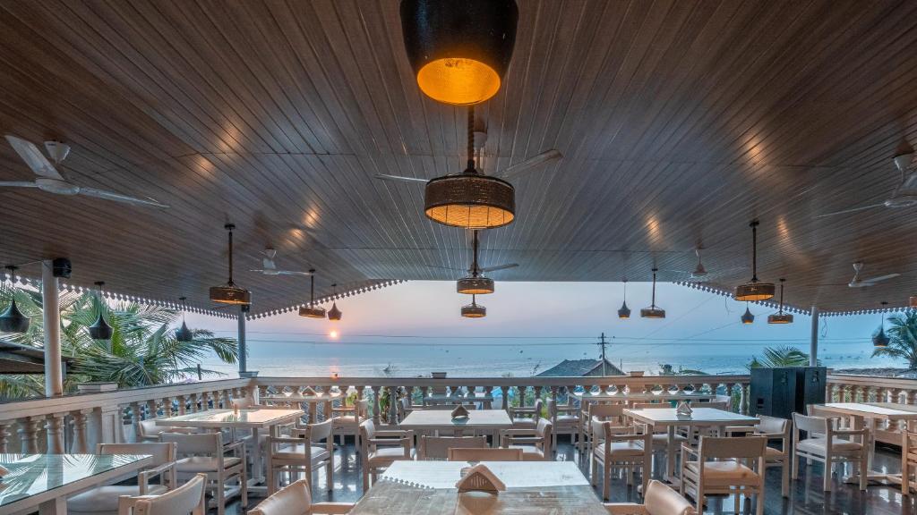 un ristorante con tavoli e sedie e vista sull'oceano di Lillywoods Zac Beach Resort, Calangute a Goa Velha