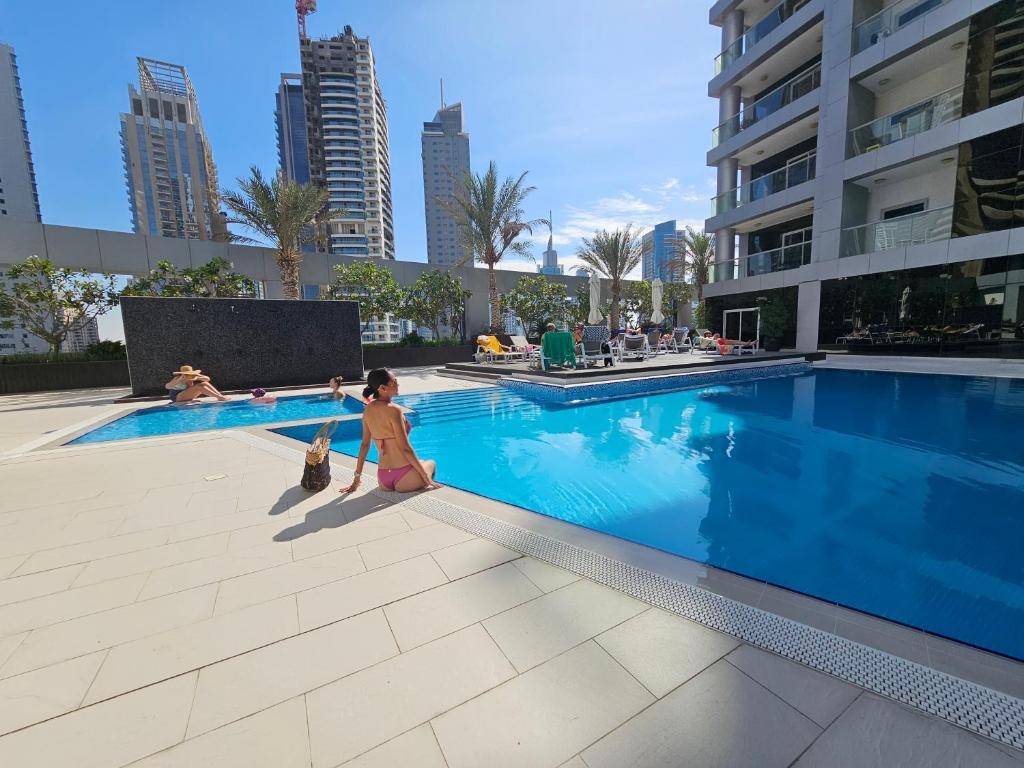 a little girl sitting next to a swimming pool at Elegant 1 BDR apt very close to JBR Beach & Marina Walk I Skyview Tower in Dubai