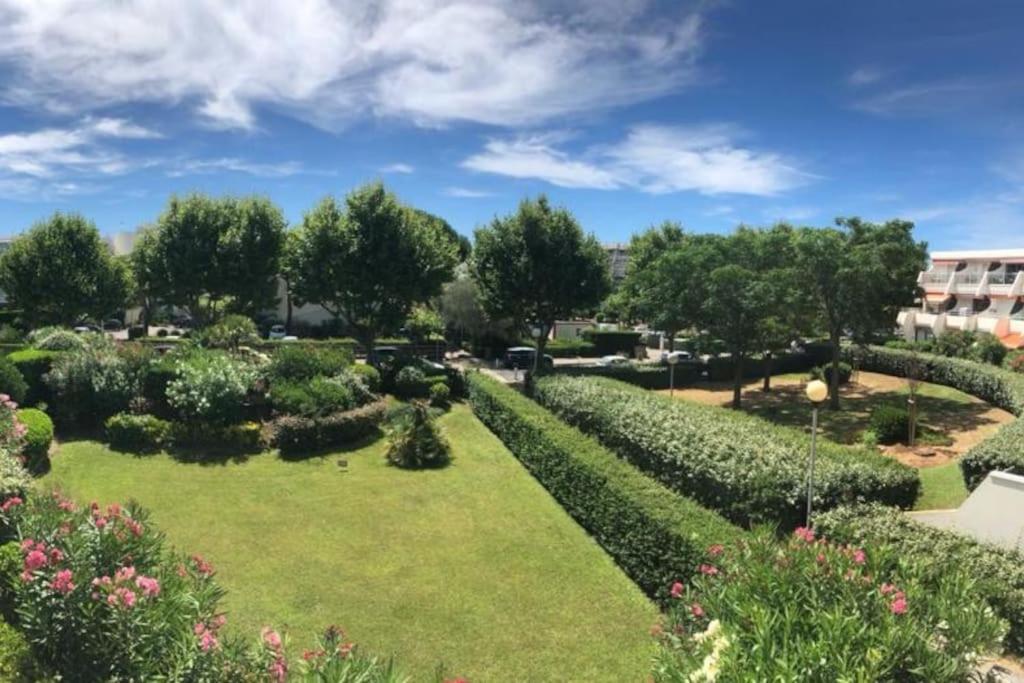 un jardin avec des haies et des arbres et un bâtiment dans l'établissement Appartement typeT2bis climatisé à 150m de la plage, à La Grande Motte