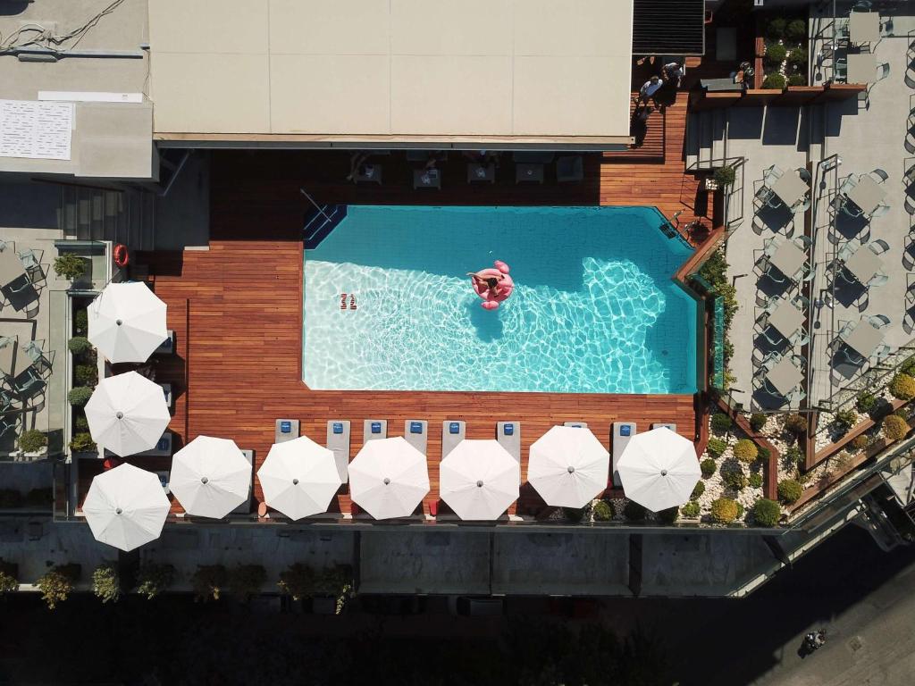 una vista sul tetto di una piscina con ombrelloni di Novotel Athens ad Atene