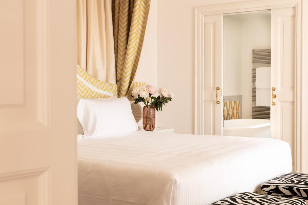a bedroom with a white bed with a vase of flowers at Il Pellicano in Porto Ercole