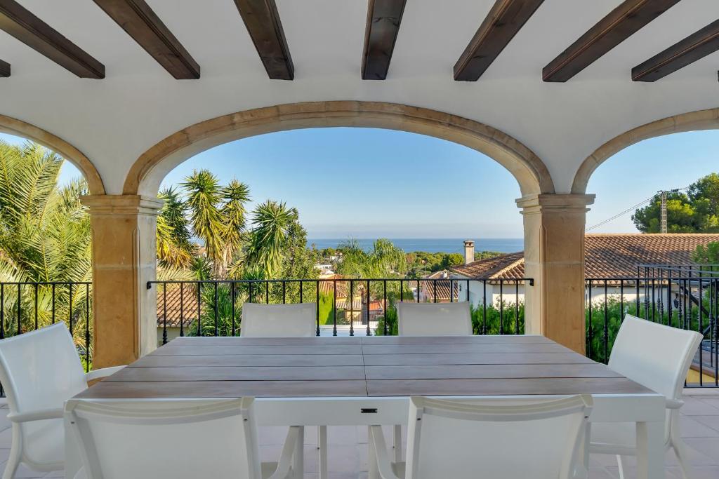 a large wooden table and white chairs on a balcony at Villa Pura Vida in Denia