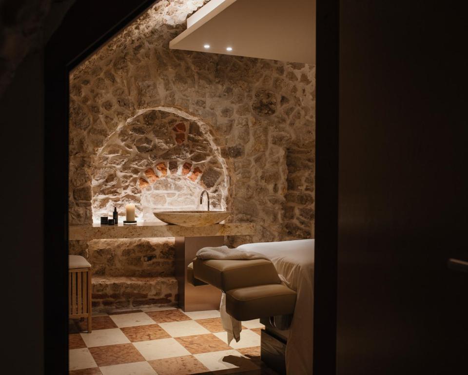 uma casa de banho com uma parede de pedra e um lavatório num quarto em Hotel Pod Różą na Cracóvia