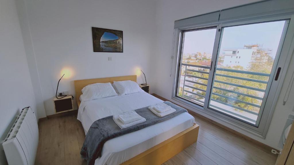 een slaapkamer met een bed en een groot raam bij STAY Mystique City Penthouse in Limassol