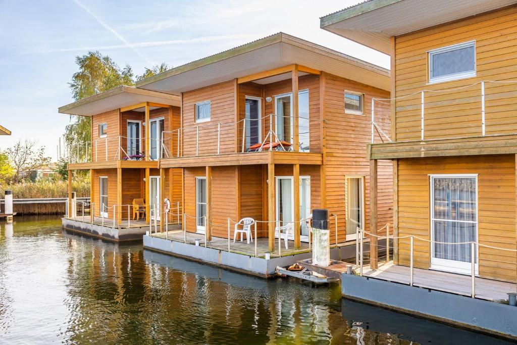 a wooden house on the water next to a river at FLOATING HOUSES Classic _ _Schwimm in Barth