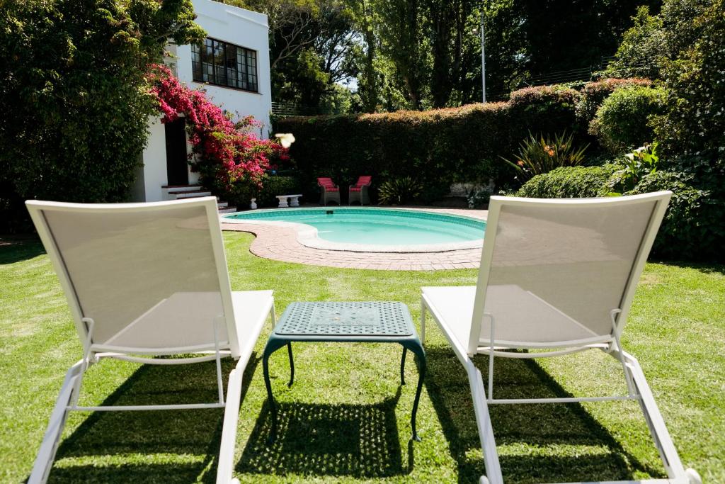 two chairs and a table next to a swimming pool at Hillingdale on Alexandra in Cape Town