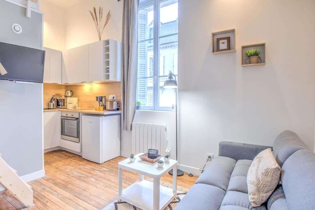 sala de estar con sofá azul y cocina en L'Esméralda en coeur de ville, en Périgueux