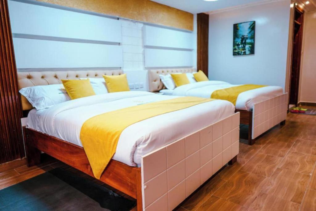 2 Betten in einem Schlafzimmer mit gelben Kissen in der Unterkunft Barre Hotel in Nairobi