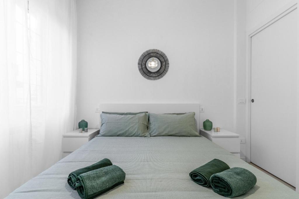 a white bedroom with a large bed with two green pillows at Apartment Milan San Siro City Life & Fiera in Milan