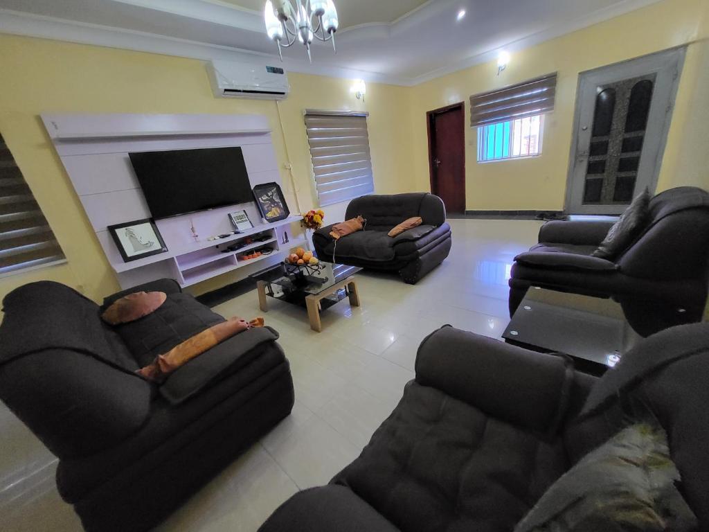 a living room with couches and a flat screen tv at Entire 3 Bedroom Bungalow - Home away from home in Lagos