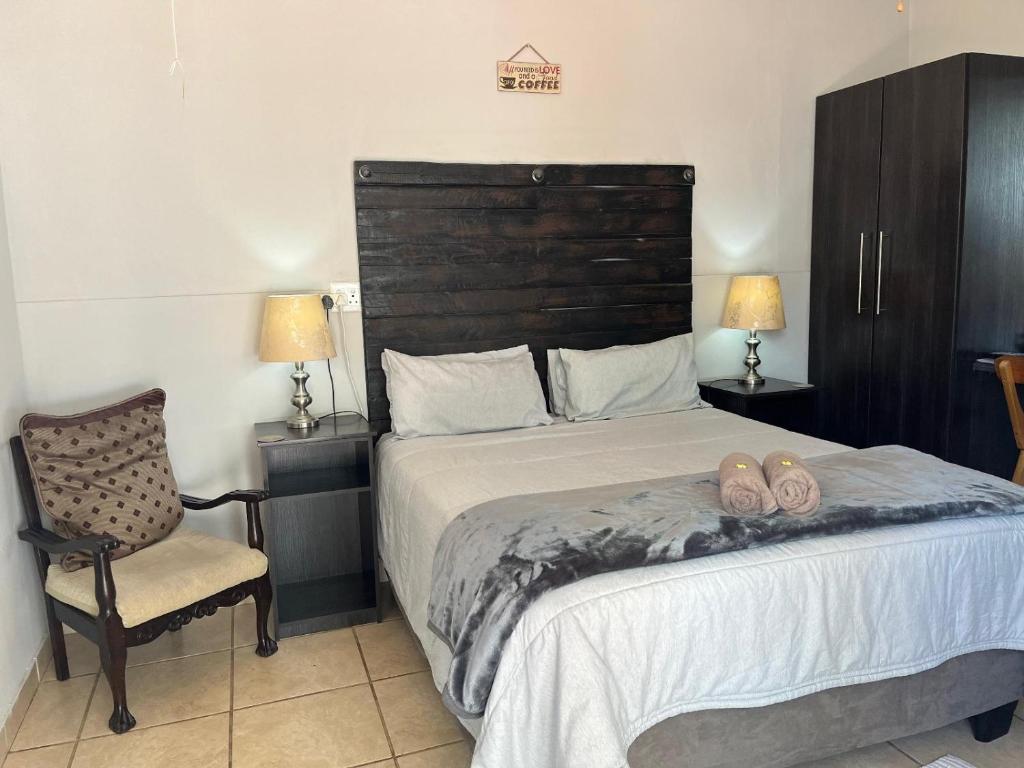 a bedroom with a bed with a chair and two slippers at La Belle Guesthouse Parys in Parys