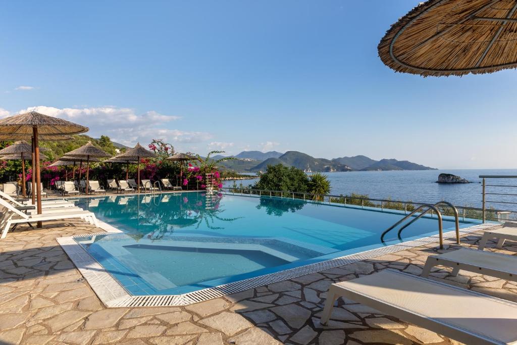 a large swimming pool next to a body of water at Costa Smeralda in Sivota