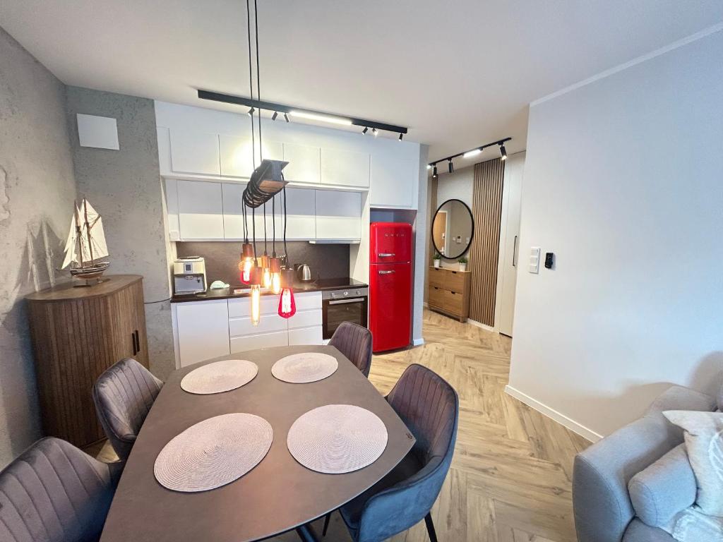 a dining room table with chairs and a red refrigerator at Apartament Brzeźno Beach in Gdańsk