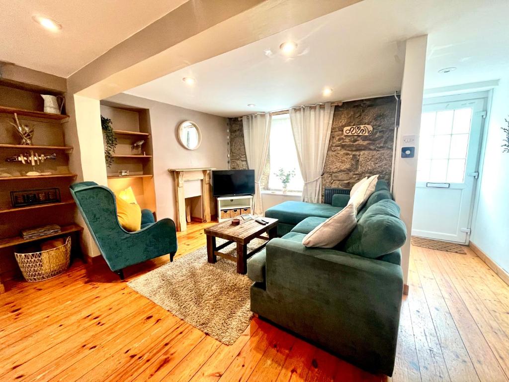 a living room with a green couch and a chair at Spaven Mor, Near Penzance Stations, 3 bedroom home in Penzance
