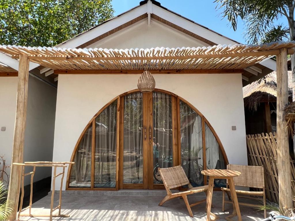 een huis met een houten deur en twee stoelen bij Rumah Canaria Bungalow in Gili Trawangan