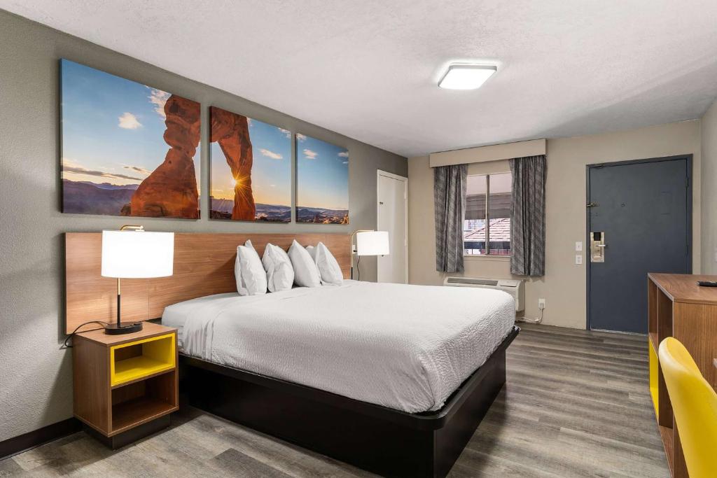 アルバカーキにあるDays inn by Wyndham Albuquerque Northeastの大きなベッドとデスクが備わるホテルルームです。