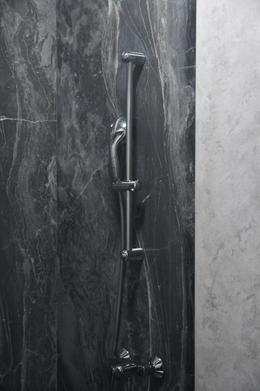 a black marble shower stall with a metal pole at Hotel Building Stefan Resort I in Mamaia Sat&#47;Năvodari