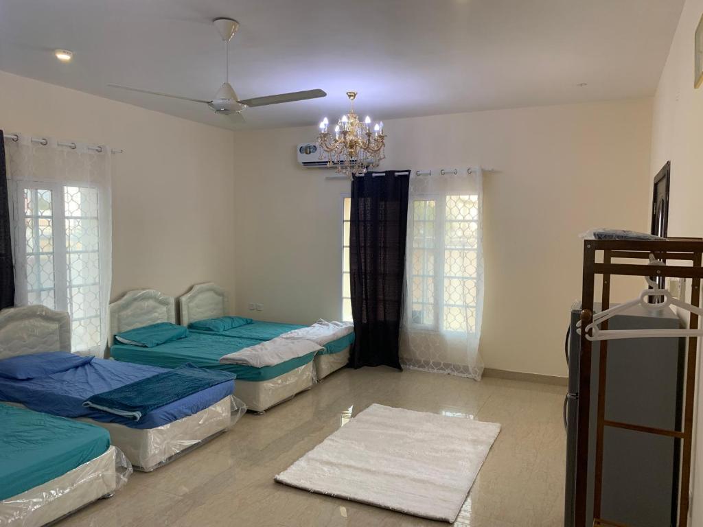 Habitación con 3 camas y lámpara de araña. en Jonoob hostel, en Mascate