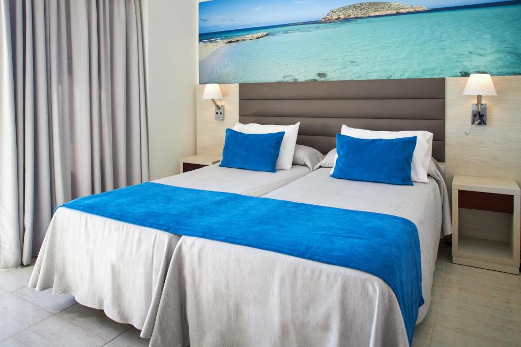 Cette chambre comprend un grand lit avec des oreillers bleus. dans l'établissement Invisa Ereso All Inclusive, à Es Cana