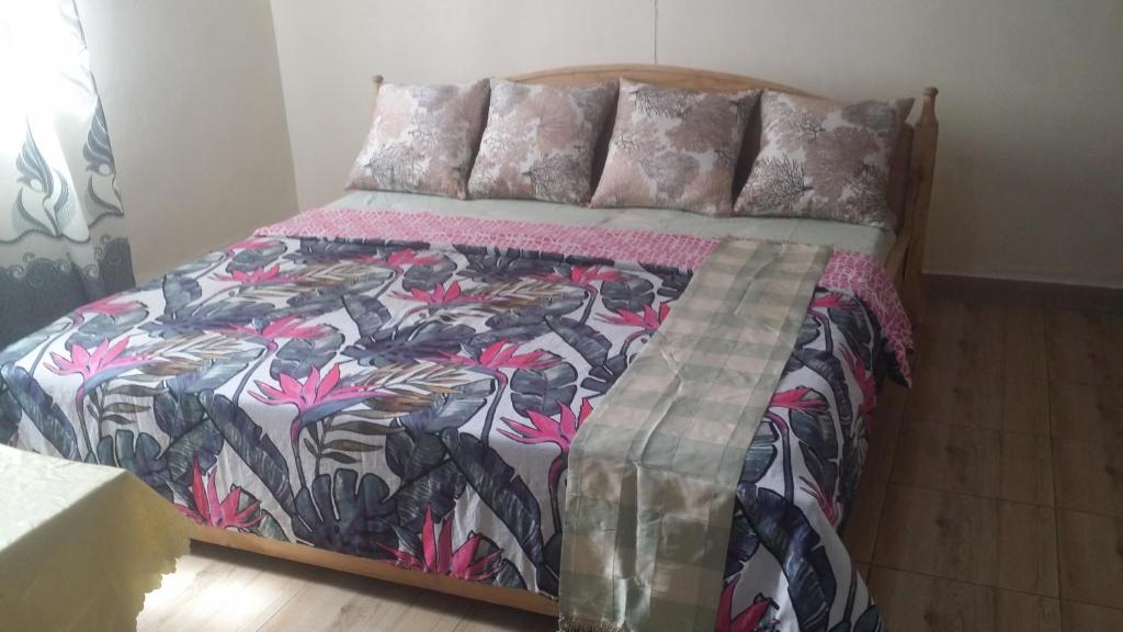 a bed with a colorful comforter and pillows at PagersHome Suites- RUSTIC in Kigali