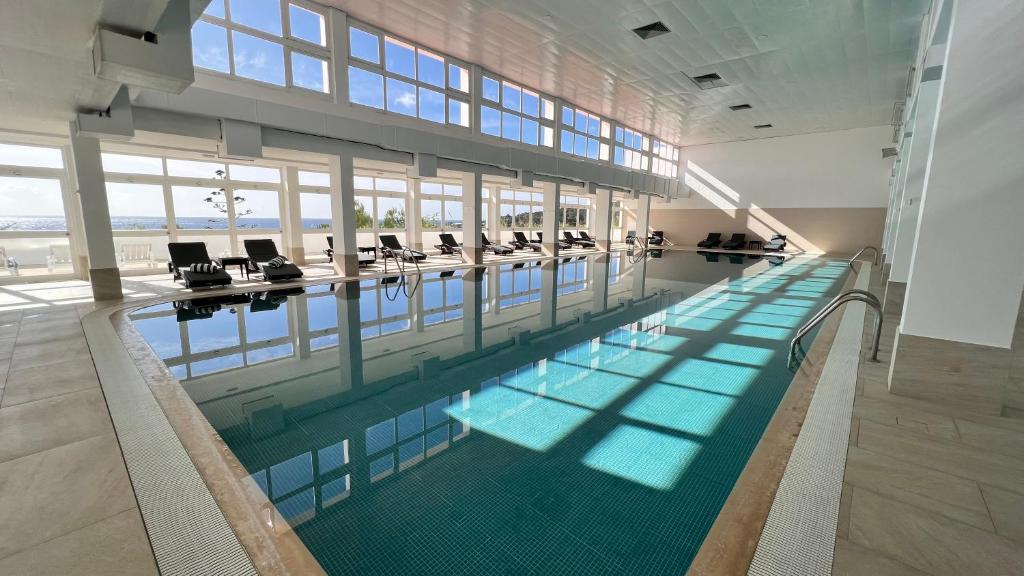 una gran piscina con sillas en un edificio en Hotel do Mar en Sesimbra