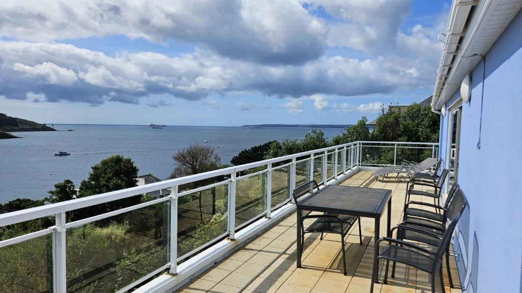a balcony with chairs and a table and a view of the water at Fiddlers Green in Saint Mawes
