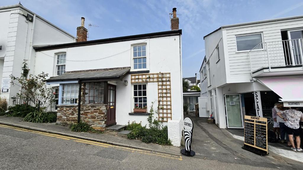 un edificio blanco al lado de una calle en Hillside Cottage, en Porthscatho