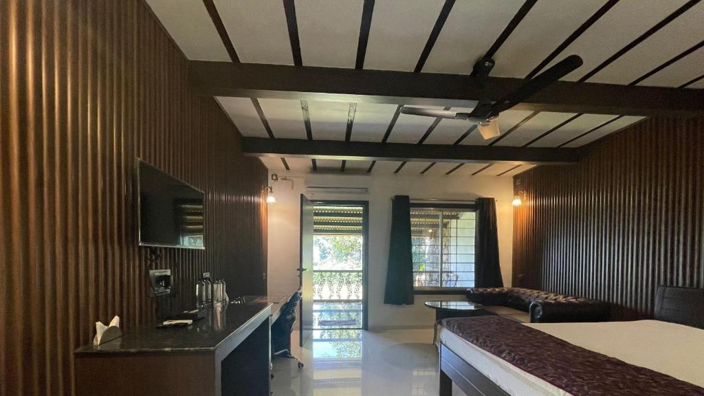 Habitación con cama, sofá y TV. en The Green Gate Resort Mulshi en Pune