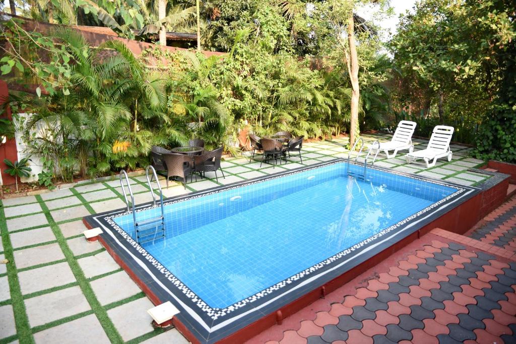 uma pequena piscina com cadeiras em 4BHK Private Pool villa in North Goa and Kayaking nearby!! em Moira