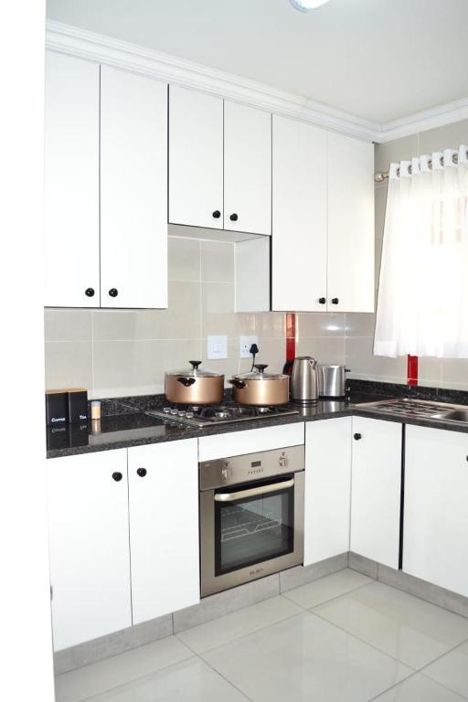 a white kitchen with white cabinets and pots and pans at Soldout Camp 2 in Pretoria