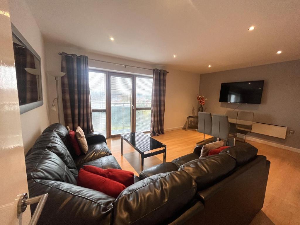 a living room with a leather couch and a television at Deluxe Large Apartment Opposite Hepworth Gallery in Wakefield