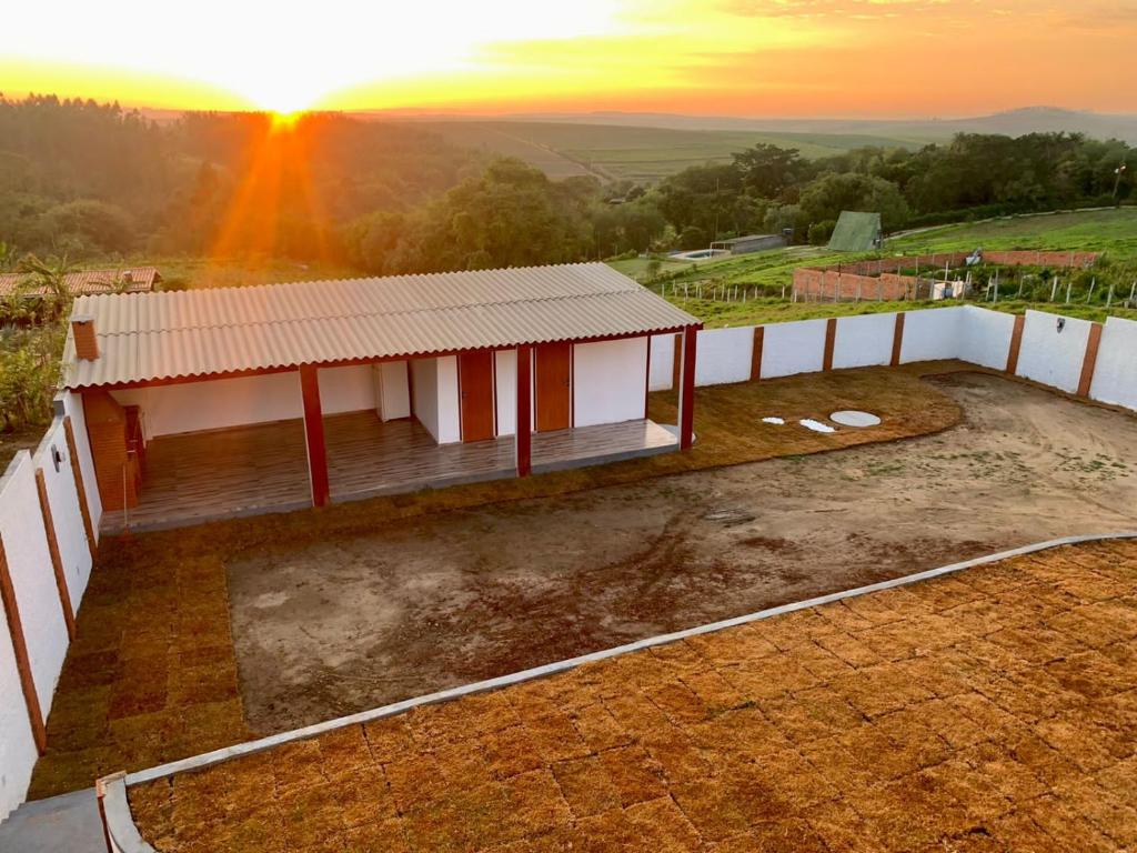 een klein huis met een zonsondergang op de achtergrond bij Casa de Campo e Pesqueiro in Pôrto Feliz