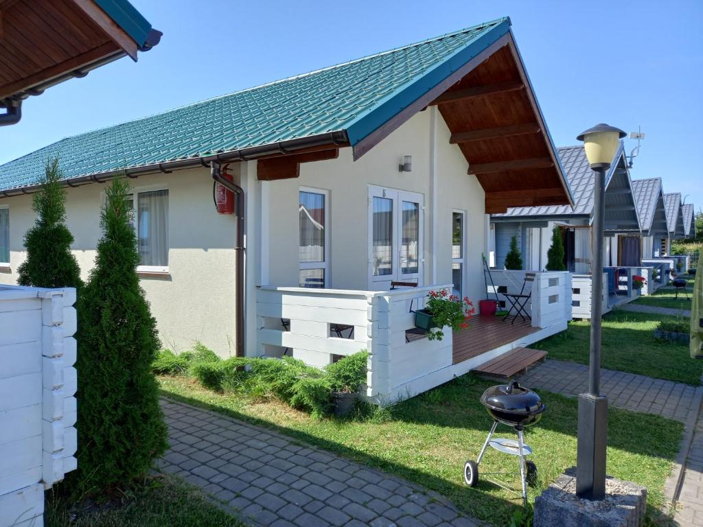 a small house with a deck and a grill at Domki Żeglarz Ustronie Morskie in Ustronie Morskie