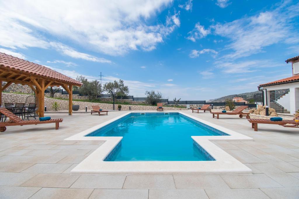 a swimming pool with benches and a gazebo at Villa Natura Piedra in Slivno