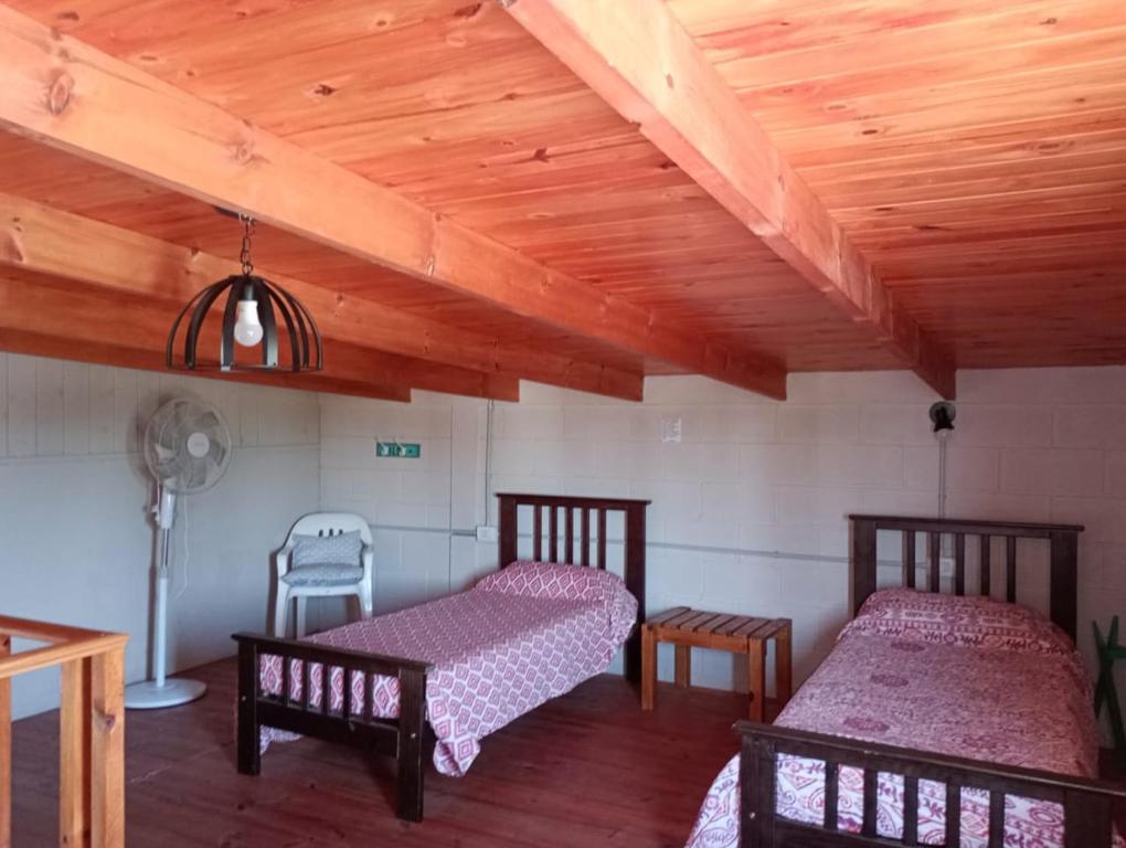 een kamer met 2 bedden en een houten plafond bij Cabaña La Rosita in Villa Quillinzo