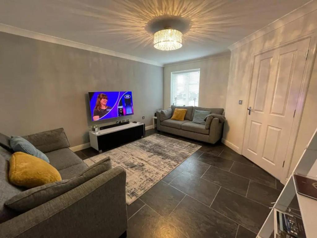 a living room with a couch and a flat screen tv at Sophisticated & Contemporary Modern House for 6 Pass the Keys in Chapel en le Frith