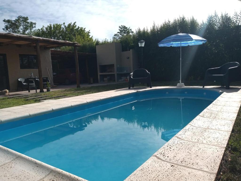 una piscina azul con sombrilla y sillas en Casa ROMA en San Rafael