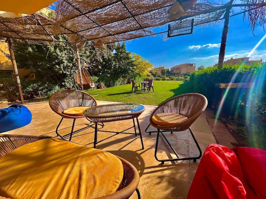 3 sillas y una mesa bajo una sombrilla de patio en 5-BRS Villa Steps from Beach Cozy vibes en Ain Sokhna