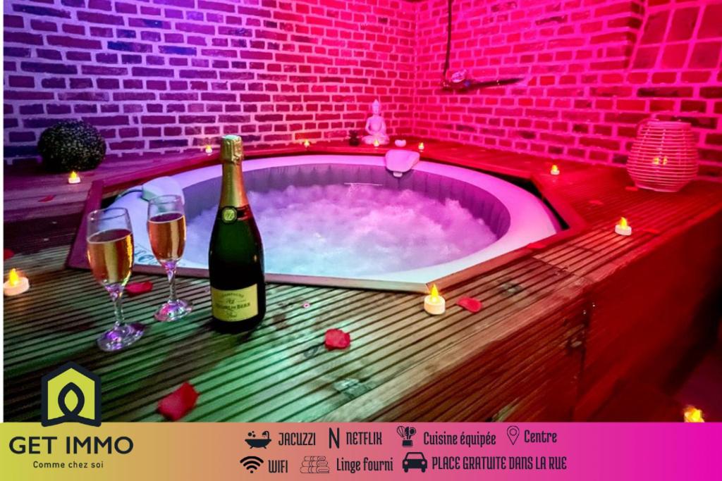 a hot tub with a bottle of wine and wine glasses at Studio Spa Privatif NETFLIX Unique Amiens in Amiens