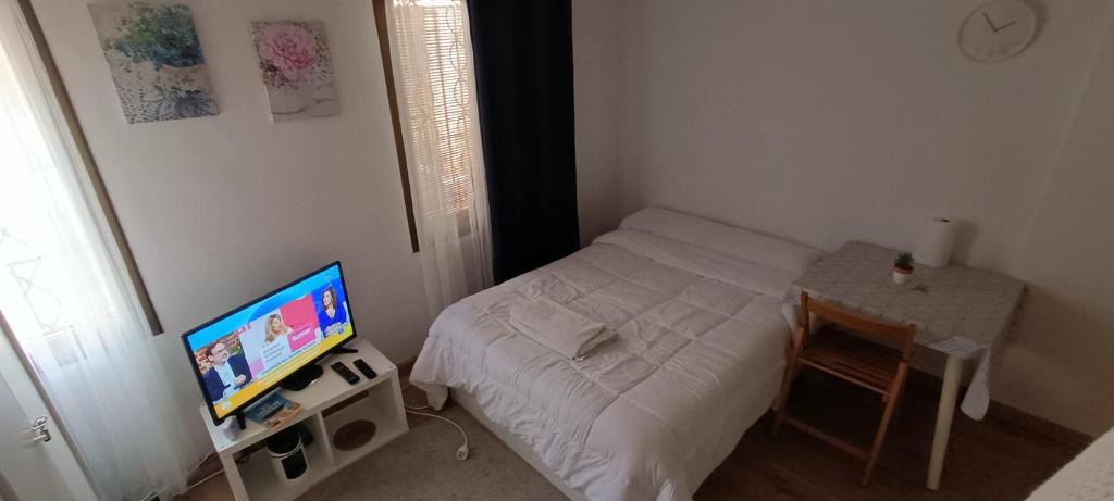 Habitación pequeña con cama y TV de pantalla plana. en Casa blanca en Santa Coloma de Gramanet