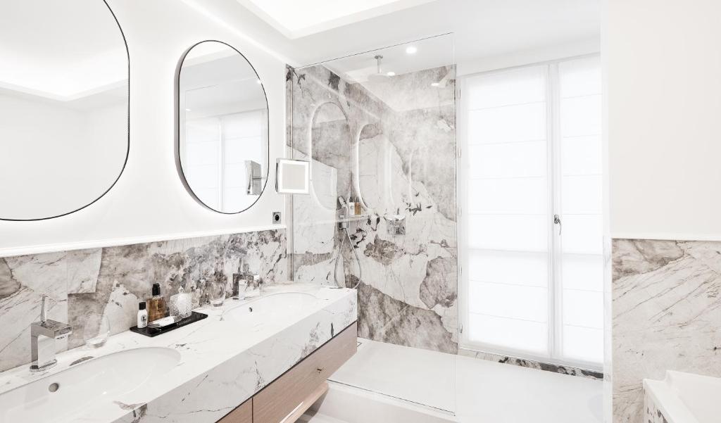 a bathroom with marble walls and a tub and a sink at Grand Hôtel Du Palais Royal in Paris