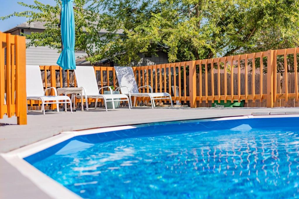 a swimming pool with chairs and umbrellas and a fence at Luxury 5br House With Pool By Seaworld & Lackland in San Antonio