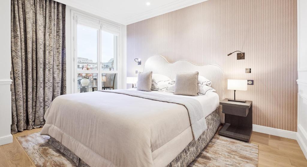 a bedroom with a large white bed with a window at Grand Hôtel Du Palais Royal in Paris